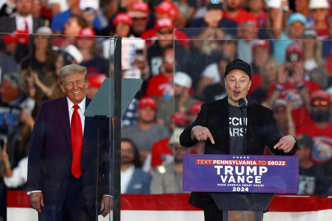 FILE PHOTO: Tesla CEO and X owner Elon Musk speaks as Republican presidential nominee and former U.S. president Donald Trump reacts during a rally at the site of the July assassination attempt against Trump, in Butler, Pennsylvania, U.S., October 5, 2024. REUTERS/Carlos Barria/File Photo
