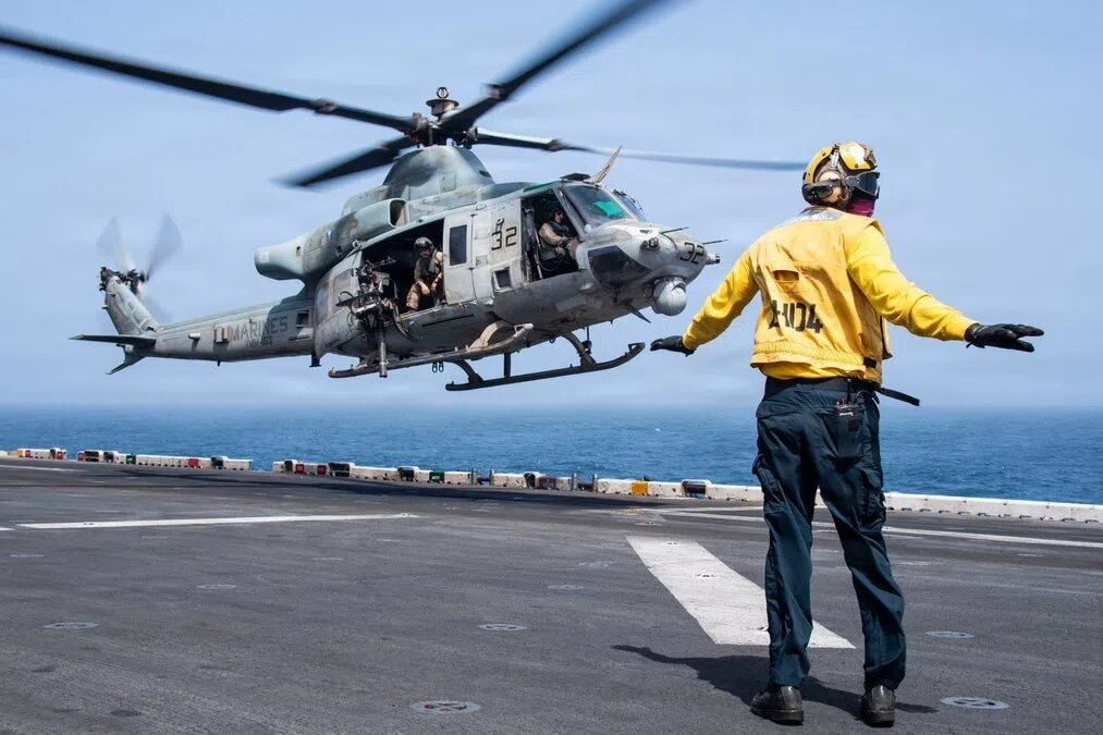 A US sailor directing the takeoff of a UH-1Y Venom utility helicopter from the flight deck of the USS Boxer, as the US enforces its blockade of Iran.