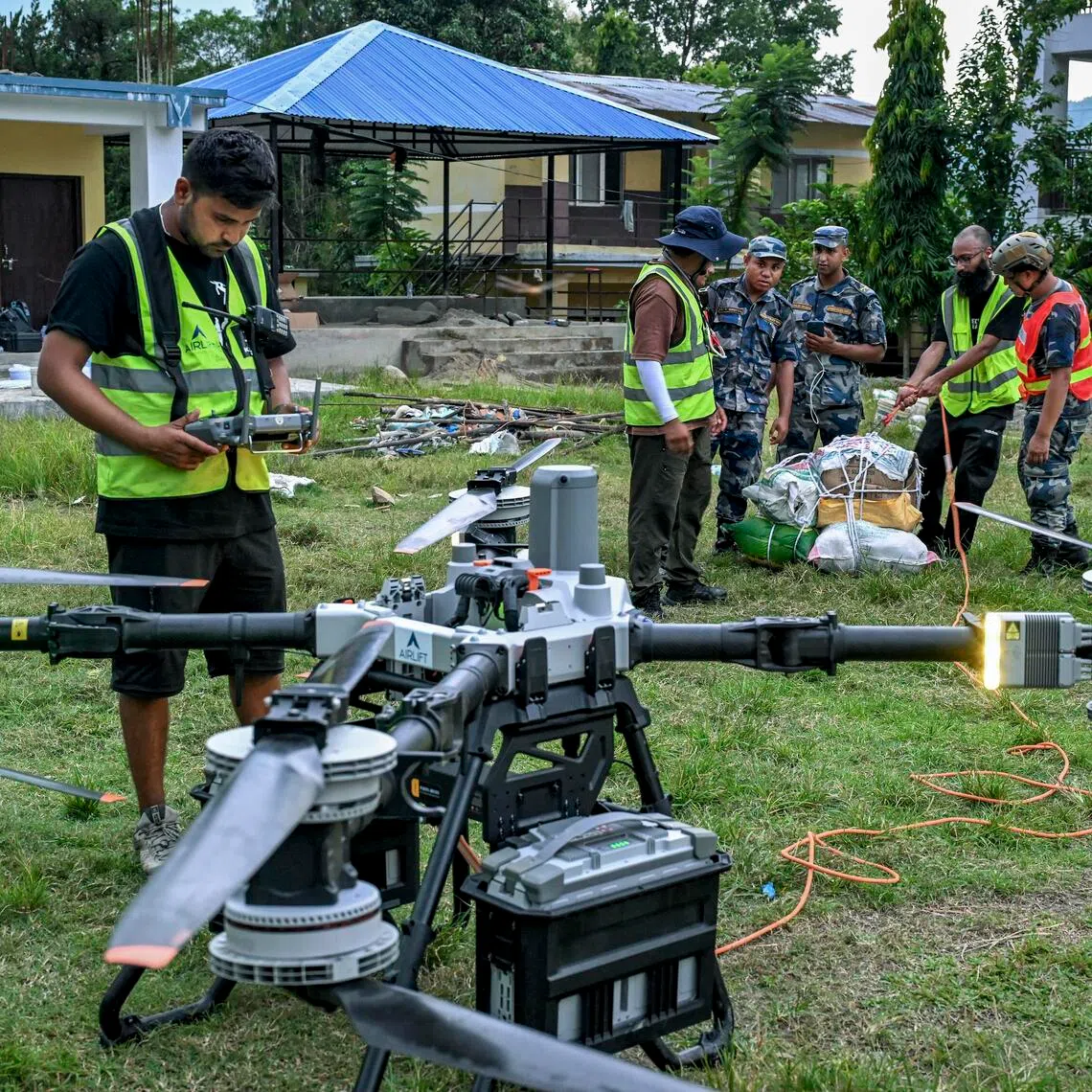 Volunteers work with police to pack essential food, medicine, and other supplies for a drone relief operation at Devighat, Nepal.