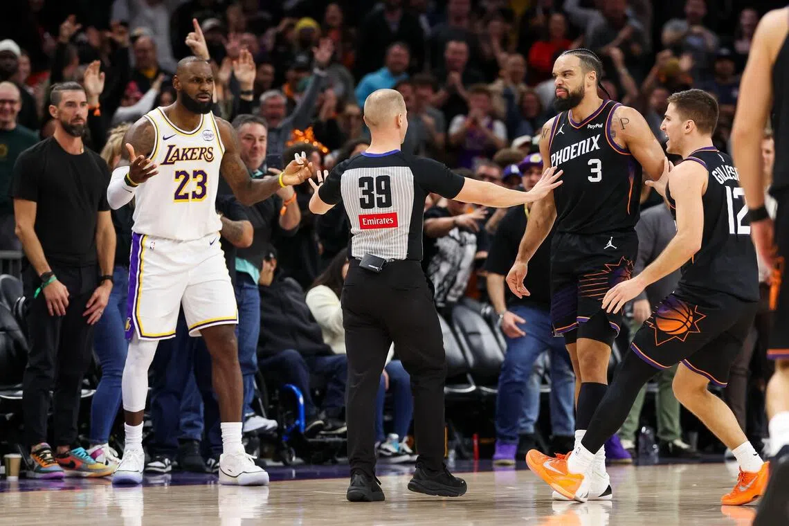 An official comes between Lebron James of the Los Angeles Lakers and Dillon Brooks of the Phoenix Suns during the second half of the NBA game at Mortgage Matchup Center on Dec 14, 2025. The Lakers prevailed 116-114, while Brooks was ejected in the dying seconds.