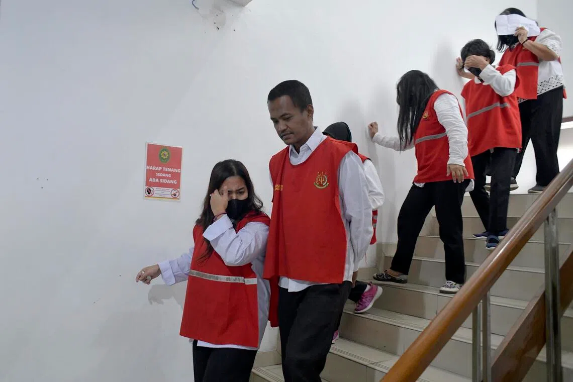 Trafficker Astri Fitrinika (left) leaves a court room at the Bandung district court in West Java. She plays a role as a recruiter in the human trafficking ring that smuggled babies to Singapore.