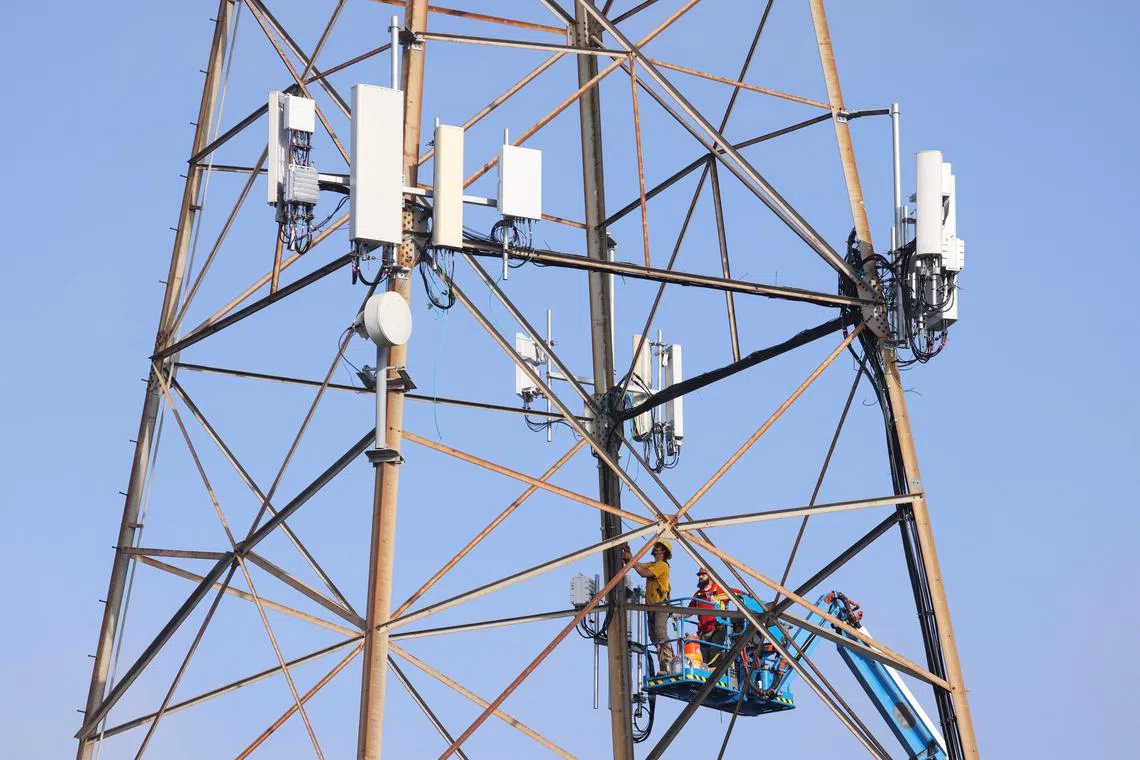 FILE PHOTO: Technicians install 5G equipment on a utilities tower in Redondo Beach, California, U.S., March 16, 2022. REUTERS/Mike Blake/File Photo