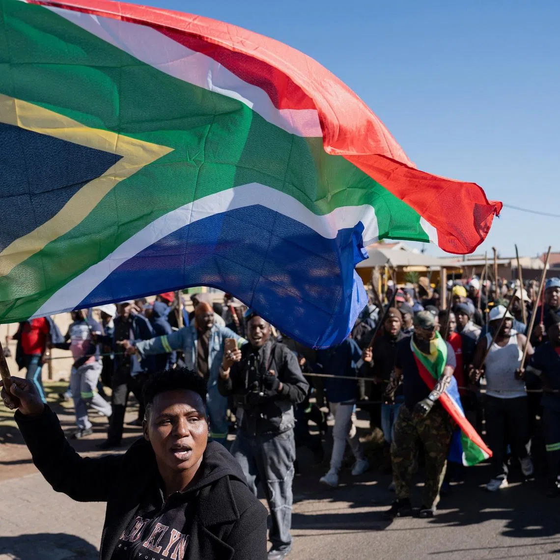 A demonstrator waves South Africa's flag during a protest calling for the deportation of undocumented immigrants, as violence against migrants from other African countries increases, in Benoni, east of Johannesburg, South Africa, June 5, 2026. REUTERS/Ihsaan Haffejee
