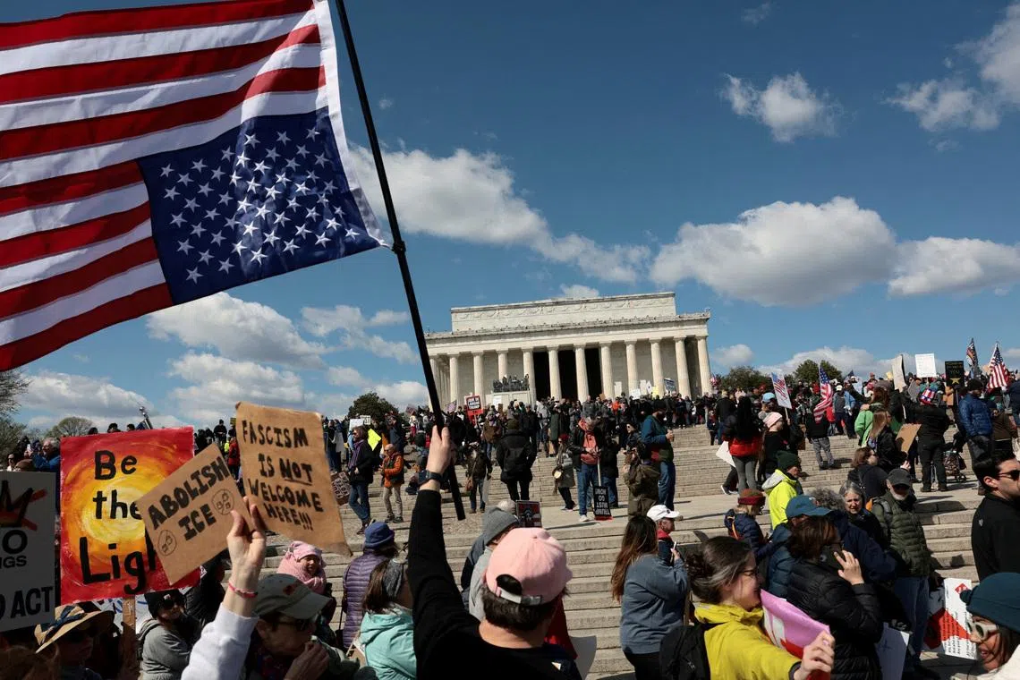 A demonstrator holds an upside-down American flag during a \"No Kings\" protest in front of the Lincoln Memorial, amid nationwide demonstrations against U.S. President Donald Trump's administration policies, in Washington, D.C., U.S., March 28, 2026. REUTERS/Evelyn Hockstein