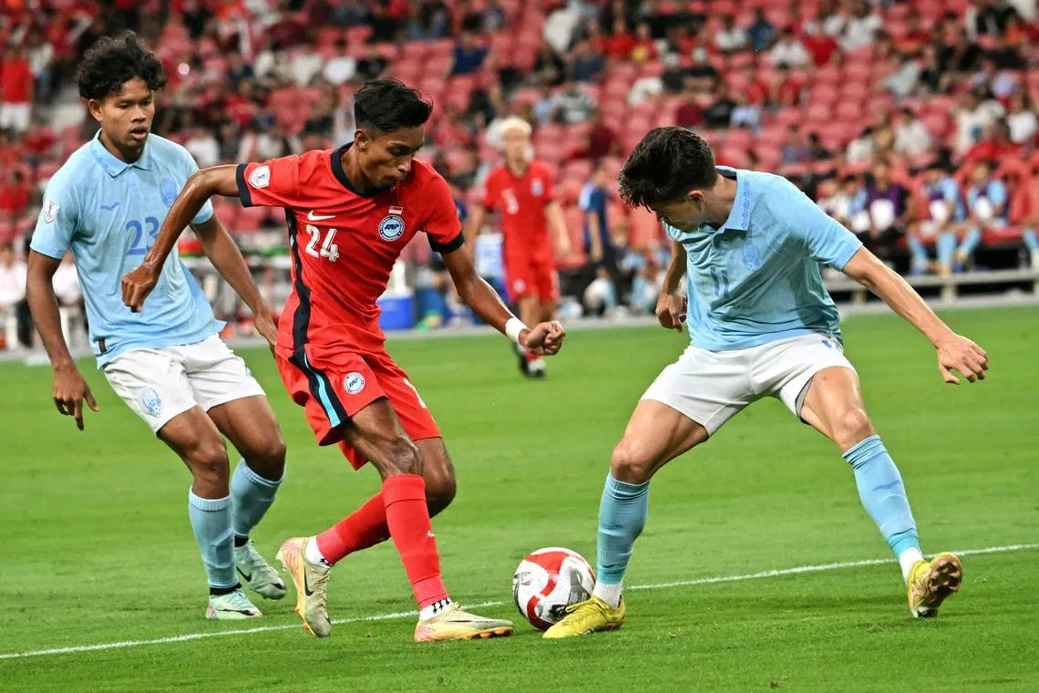 Singapore player (in red) Naqiuddin Eunos against Cambodia players during the AFF Championship Group A match at the National Stadium on Dec 11.