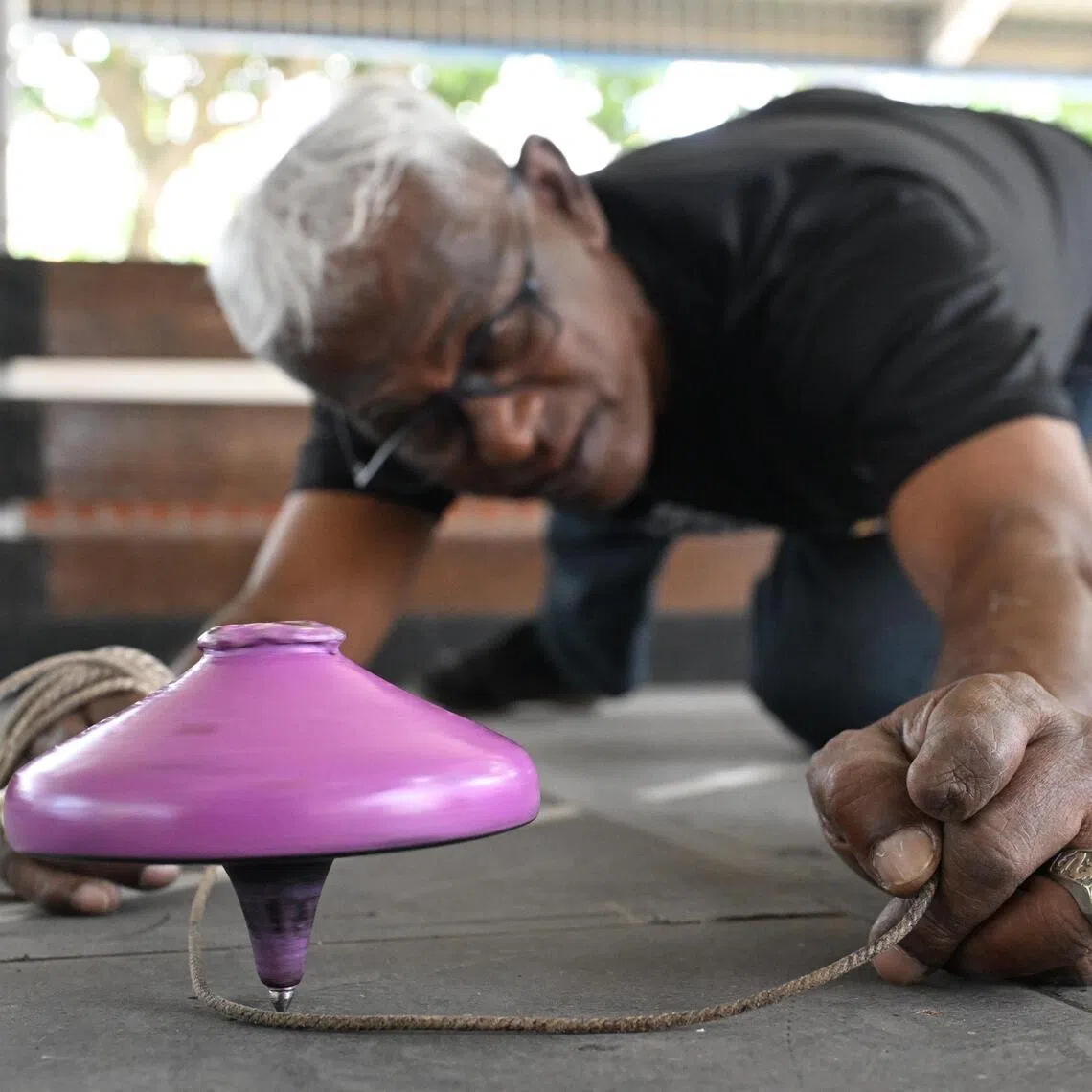 Noorul Hayath adjusting his gasing as it spins during a game at the Kolam Ayer Gasing & Games Court on Jan 5, 2026.
