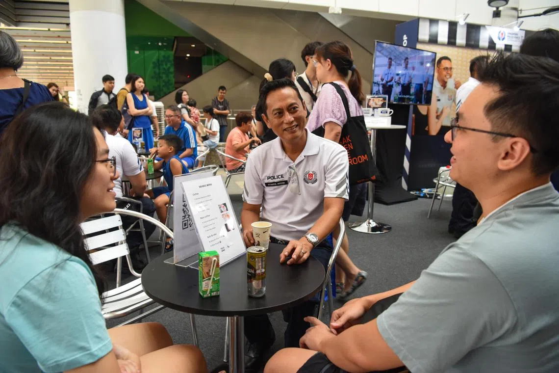 Police Officer Syamsul Hidzam talking to members of the public at the Coffee with a Cop booth at the Police Community Roadshow on June 17, 2023.