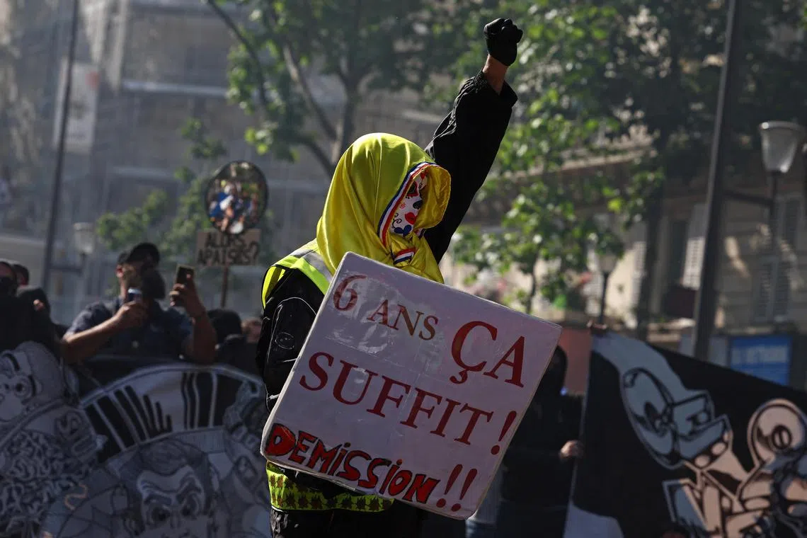 A protester in Paris holds a placard which reads "6 years is enough, resign!" during a demonstration over pension reforms.