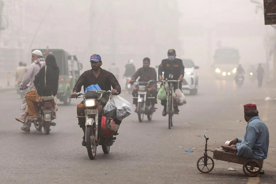 Cars and motorbikes drive along a street engulfed in smog on Nov 8.