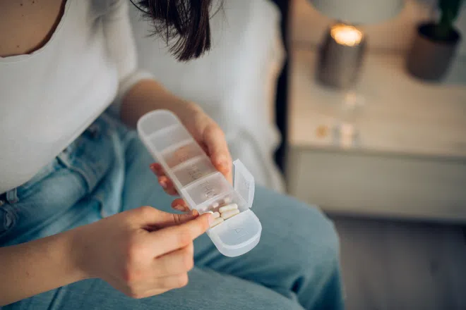 Woman taking magnesium supplement from pill box
