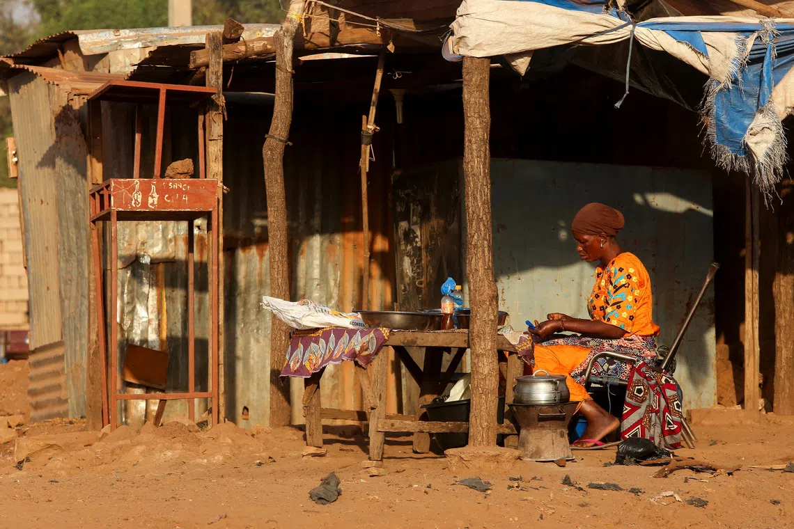 A woman prepares food on the road side, amid ongoing fuel shortages caused by a blockade imposed by al Qaeda-linked insurgents in early September, in Bamako, Mali, October 31, 2025. REUTERS/Stringer