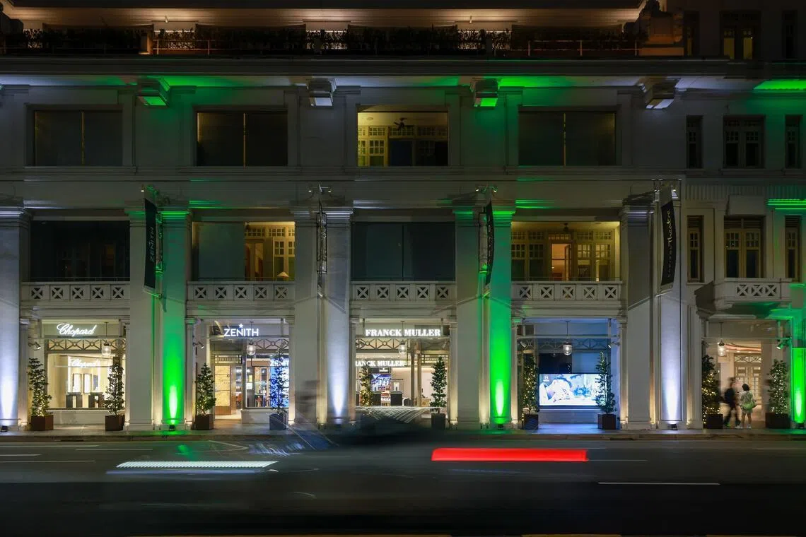 Vehicles zooming past Capitol Singapore as it is illuminated with green and white lighting on June 26.