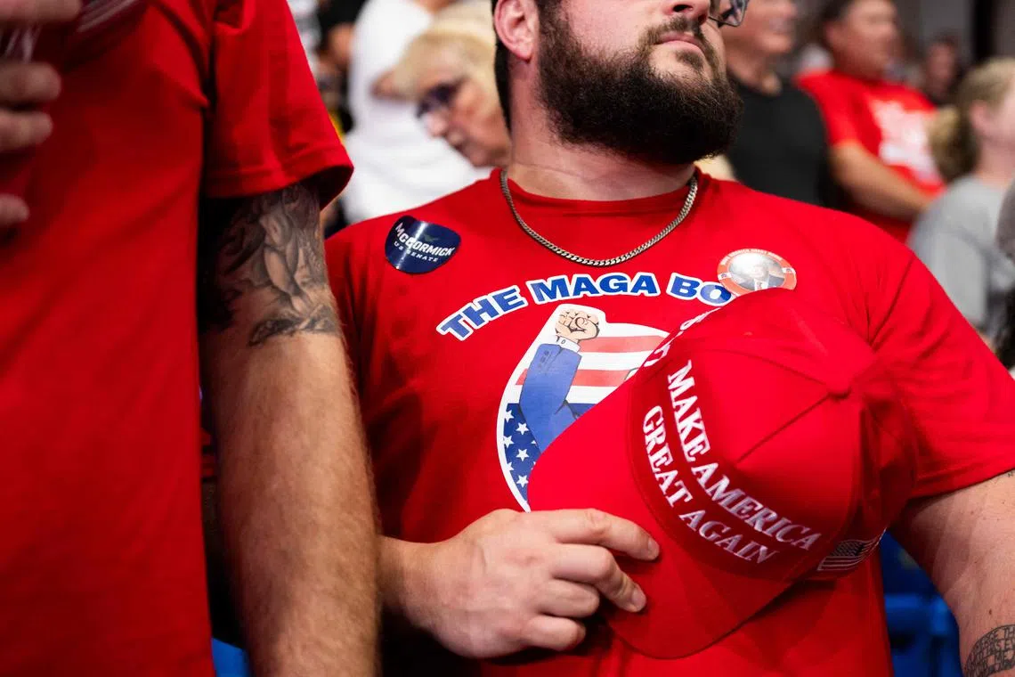 A tattooed Millennial cryptocurrency investor wears a MAGA BOYZ t-shirt during a political rally where former US President and presidential candidate Donald Trump spoke.