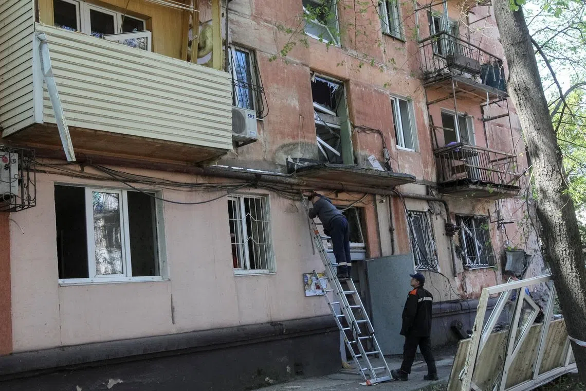 Municipal employees work at a site of an apartment building hit by a Russian drone strike, amid Russia's attack on Ukraine, in Dnipro, Ukraine, on May 7.