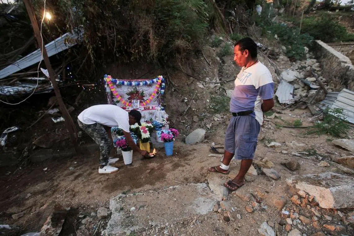 Candido Trinidad de la Cruz, 40, (R) who lost his family and home during Hurricane Otis, stands next to an altar placed in their memory at the place where their house used to be, on Christmas Eve, in Acapulco, Mexico December 24, 2023. REUTERS/Javier Verdin