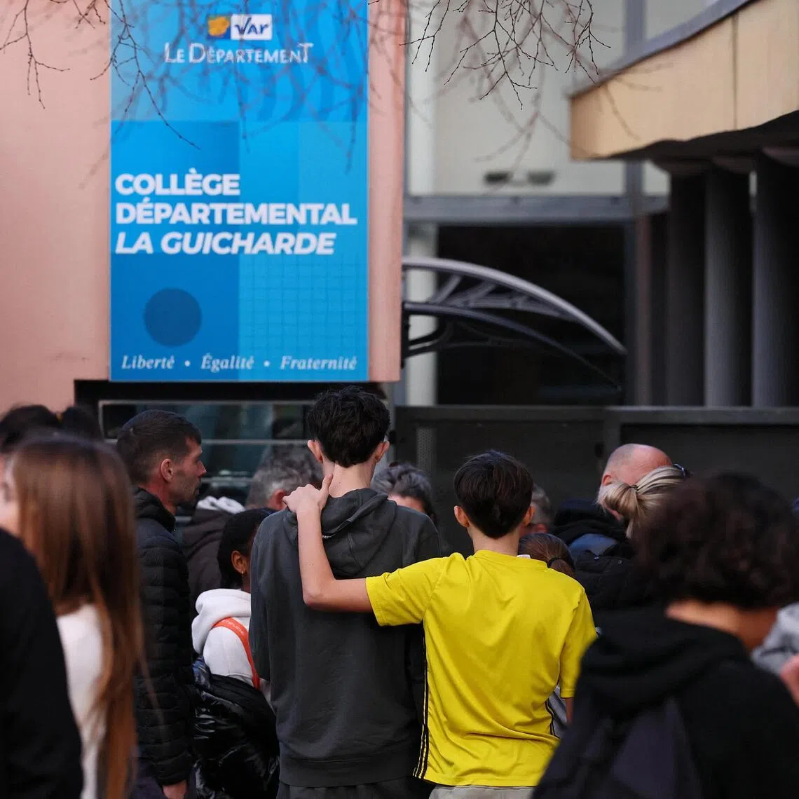 Students and their parents stand in front of the La Guicharde middle school after a teacher was seriously injured after being stabbed by a student on Feb 3.
