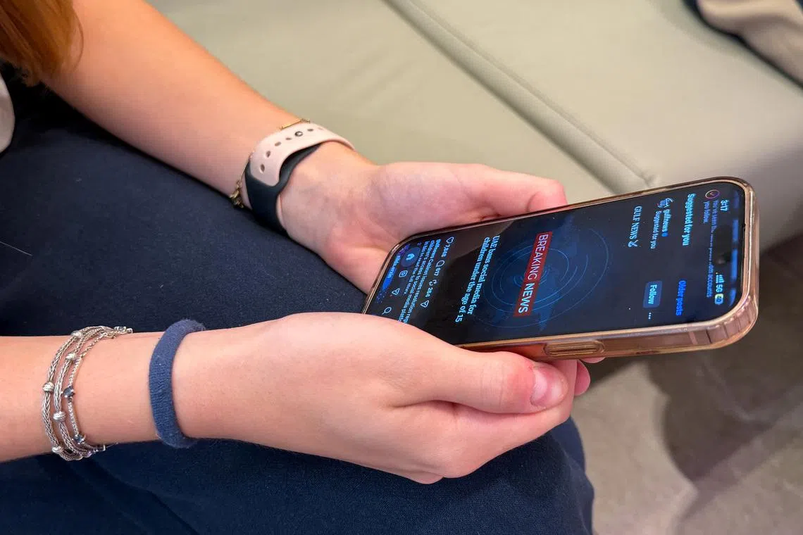A teenage girl holds her mobile phone displaying a news alert on social media, after the United Arab Emirates approved a resolution setting the minimum age for social media use at 15, in Dubai, United Arab Emirates, June 18, 2026. Picture taken with a mobile phone. REUTERS/Rula Rouhana
