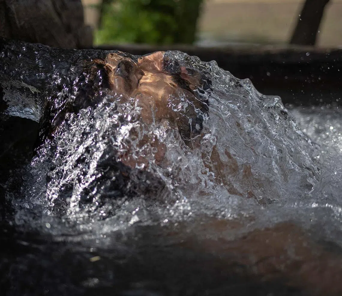 Faisal, 18, a truck driver, cooling off in groundwater being pumped to irrigate nearby fields as temperatures soared above 48 deg C during a heatwave in Daska, Pakistan, June 10, 2025. 