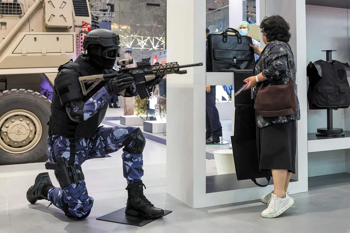 A visitor views a bag displayed next to a mannequin holding an assault rifle and displaying an urban combat uniform at the 13th edition of the Milipol Qatar 2024 homeland security and civil defence exhibition in Doha on Oct 29, 2024.