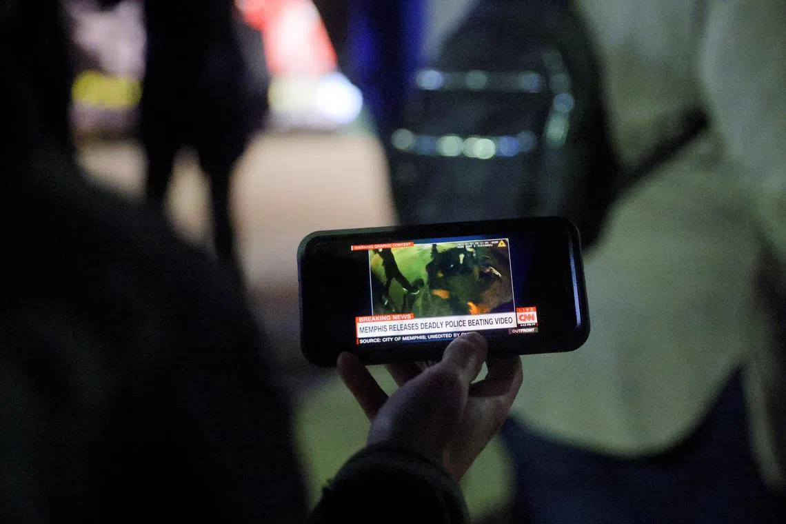 A protestor watches a video showing the Memphis police beating of Tyre Nichols, the young Black man who died while hospitalised three days later. 