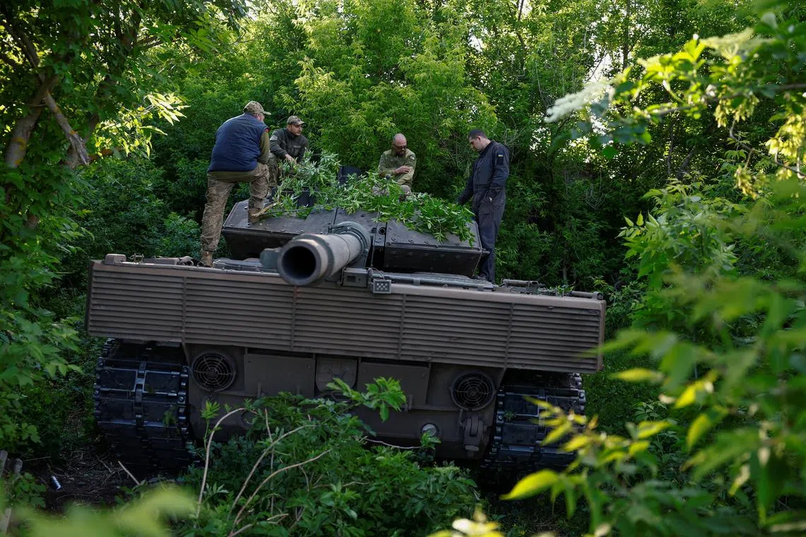 Ukrainian servicemen rest atop a Leopard 2A6 tank, after a military exercise in Ukraine's Donetsk region.