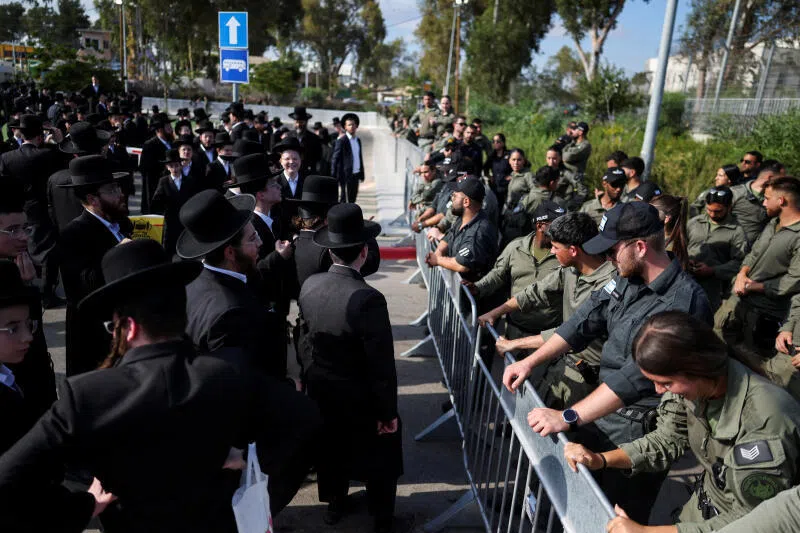 Israeli security forces standing guard as Ultra-Orthodox Jewish men gather during a protest against conscription pressure outside a military prison near Kfar Yona, Israel, in June.