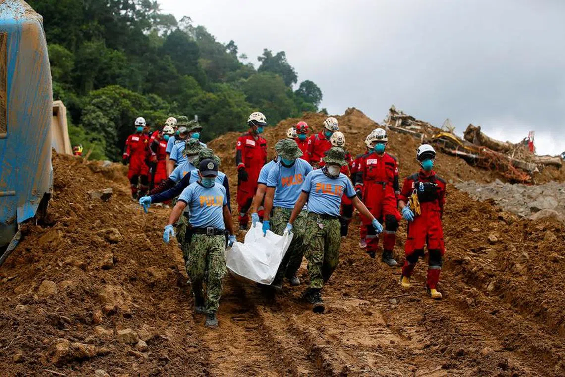 Police officers carry a body bag as search and rescue operations continue in the landslide-hit village of Masara, Maco, Davao de Oro, Philippines, February 8, 2024. REUTERS/Mark Navales