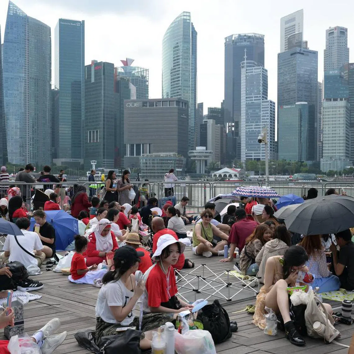 People were out in force with umbrellas and picnic mats as they gathered ahead of the National Day Parade on Aug 9.