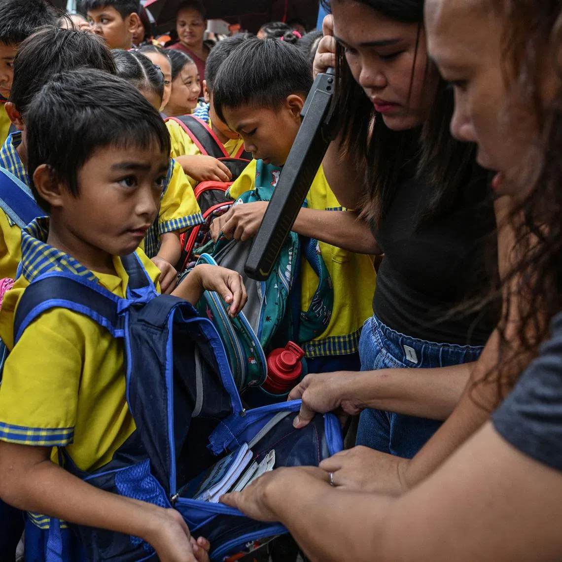 A parent assists in the checking of students' bags as they enter President Corazon Aquino Elementary School, a day after at least three students were killed and seven others injured when two students, aged 15 and 14, opened fire at a school in the city of Tacloban southeast of Manila, in Quezon City, Philippines, June 23, 2026. REUTERS/NOEL CELIS