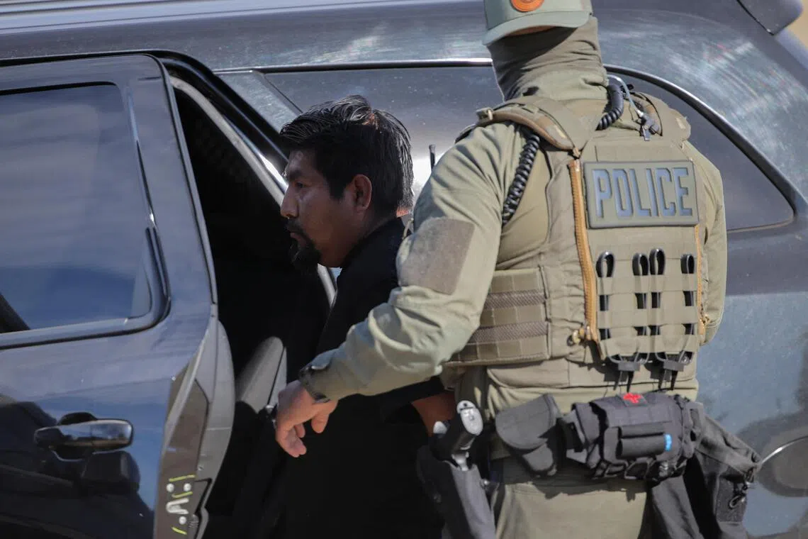 A US Immigration and Customs Enforcement (ICE) agent detaining a man during an immigration raid in Thermal, California, on Dec 19.
