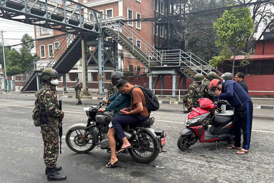 Army personnel inspect identity documents of commuters along a street as part of security measures imposed in Kathmandu on Sept 10.