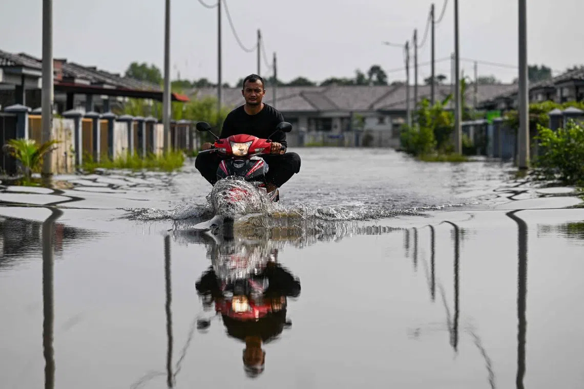 A man rides a motorbike in floodwaters after heavy rain in Pasir Mas, Malaysia's Kelantan state on Dec 3, 2024.