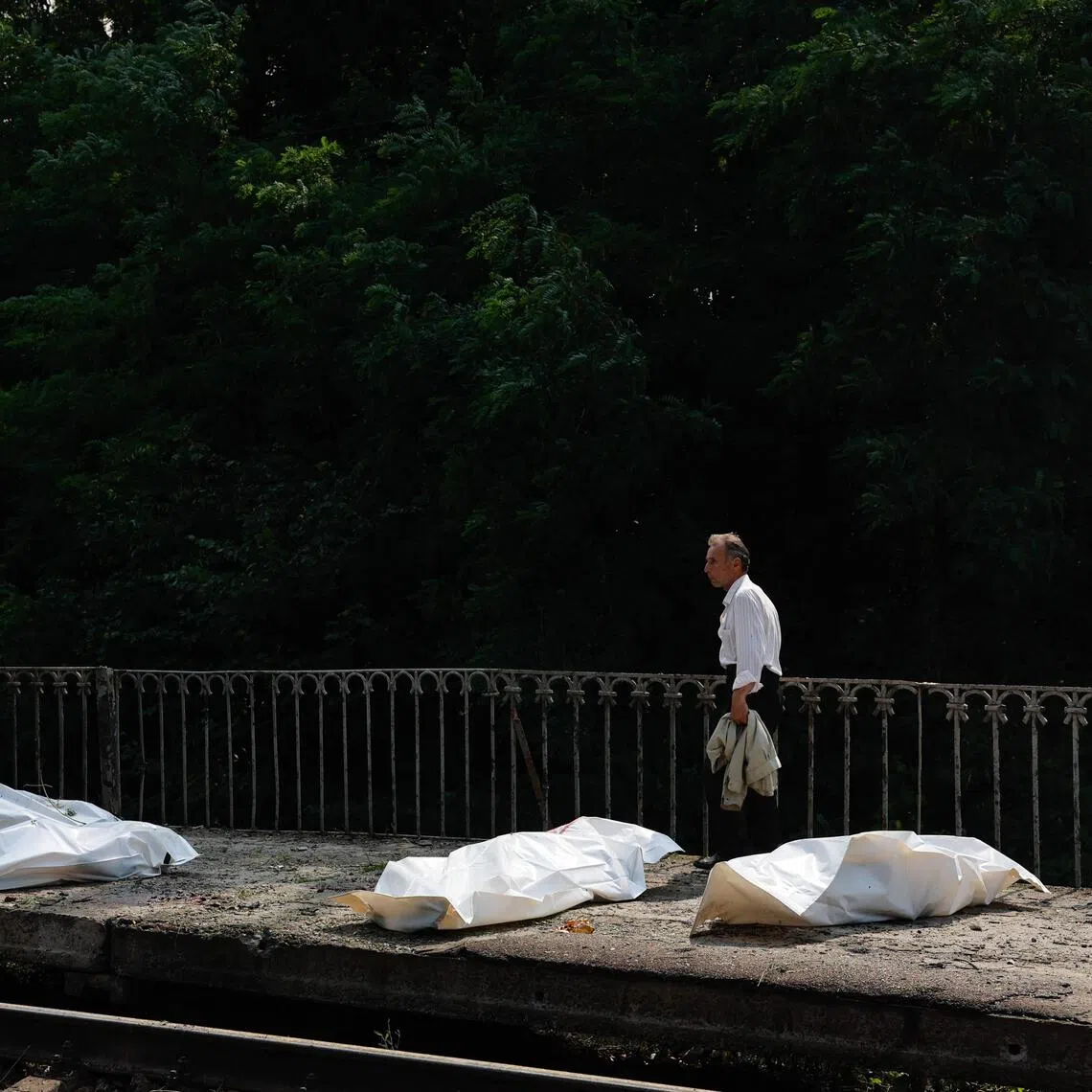 A man walking past plastic bags containing the bodies of people killed at a railway station in the Kyiv region on Aug 5, during Russian ballistic missile and drone strikes.