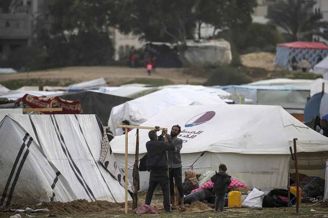 Palestinians who fled from the northern Gaza Strip sit outside their shelters in Deir Al Balah, Gaza Strip.