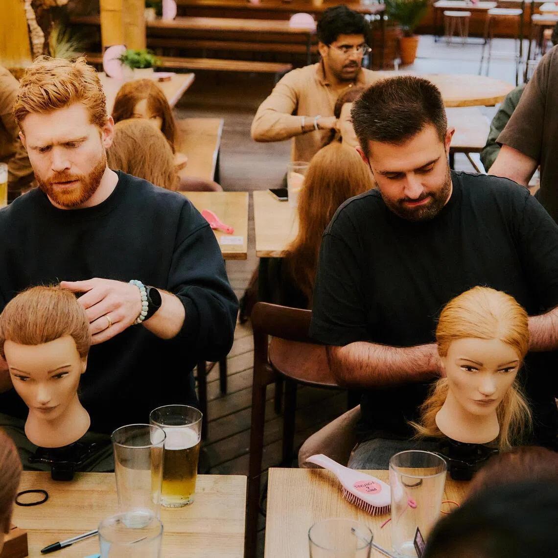 Fathers using mannequins to learn about hairstyling children at a “Pints and Ponytails” happy hour at a rooftop bar in South London on May 19.