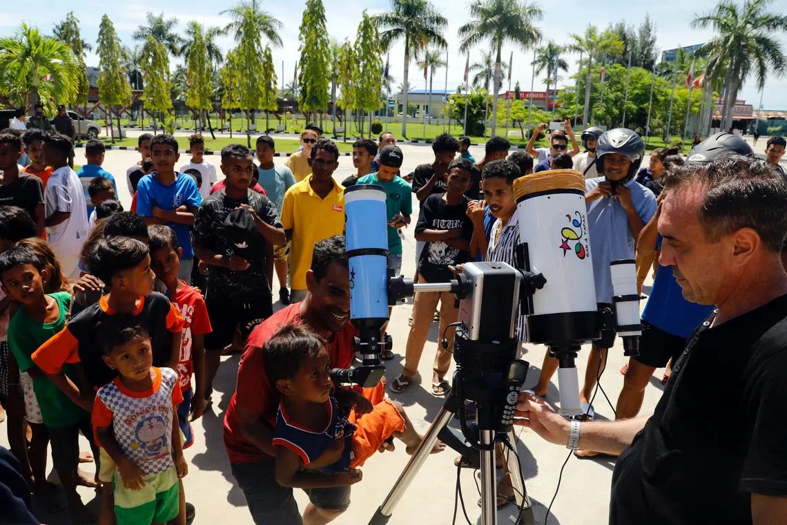 East Timorese people use a telescope as they watch a solar eclipse in front of the Presidential office in Dili, East Timor, April 20, 2023. 