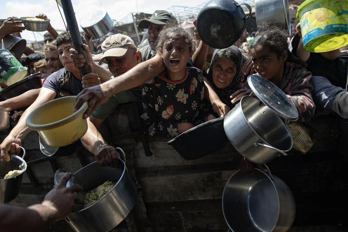 Internally displaced Palestinians scramble for food donated by a charity at a camp in Khan Younis in southern Gaza.