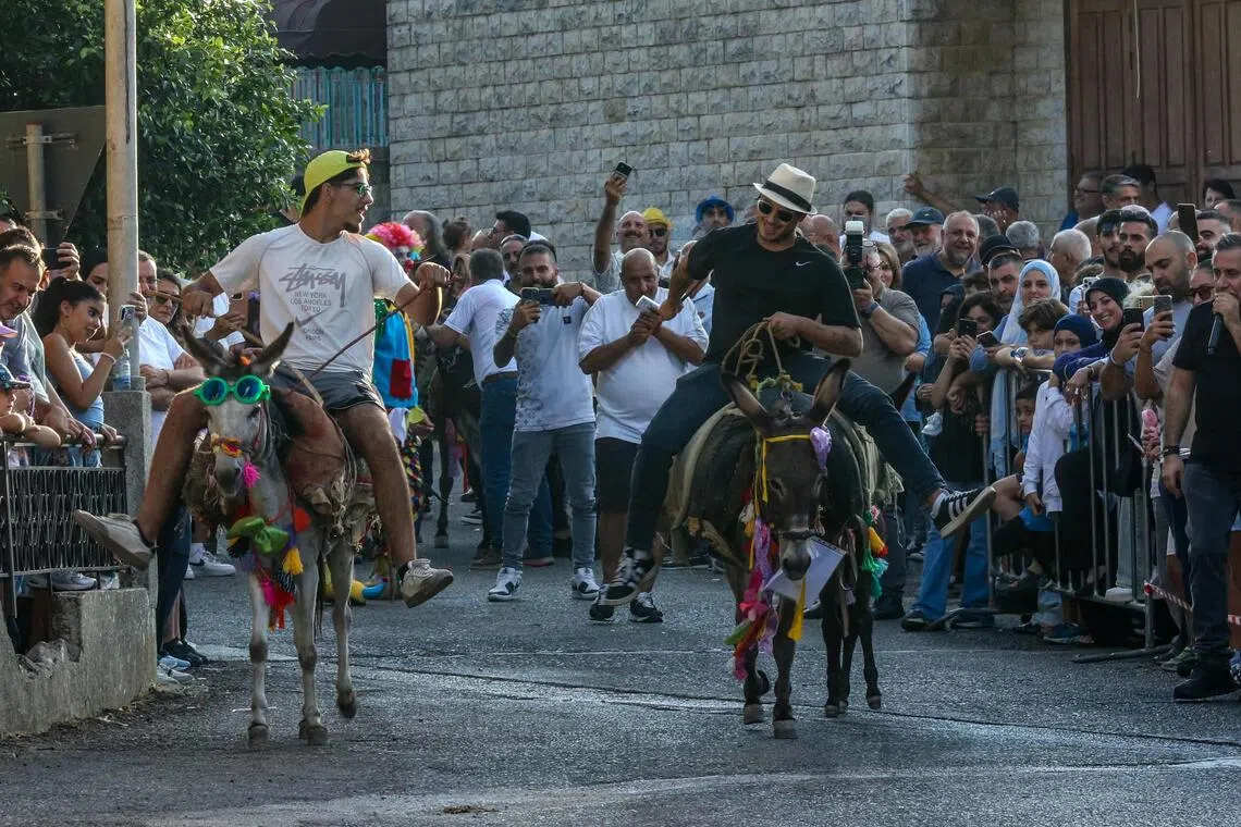 TOPSHOT - People race donkeys through the streets of the southern Lebanese town of Roum during its annual summer festival, a tradition dating back to 1964, near the city of Jezzine on September 6, 2026. (Photo by Mahmoud ZAYYAT / AFP)