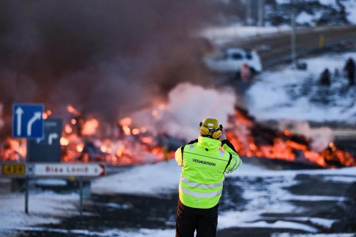 A road agency staff taking a picture of the molten lava on Feb 8, 2024, along the road leading to the famous tourist destination Blue Lagoon, a luxury geothermal spa, which is temporarily closed.
