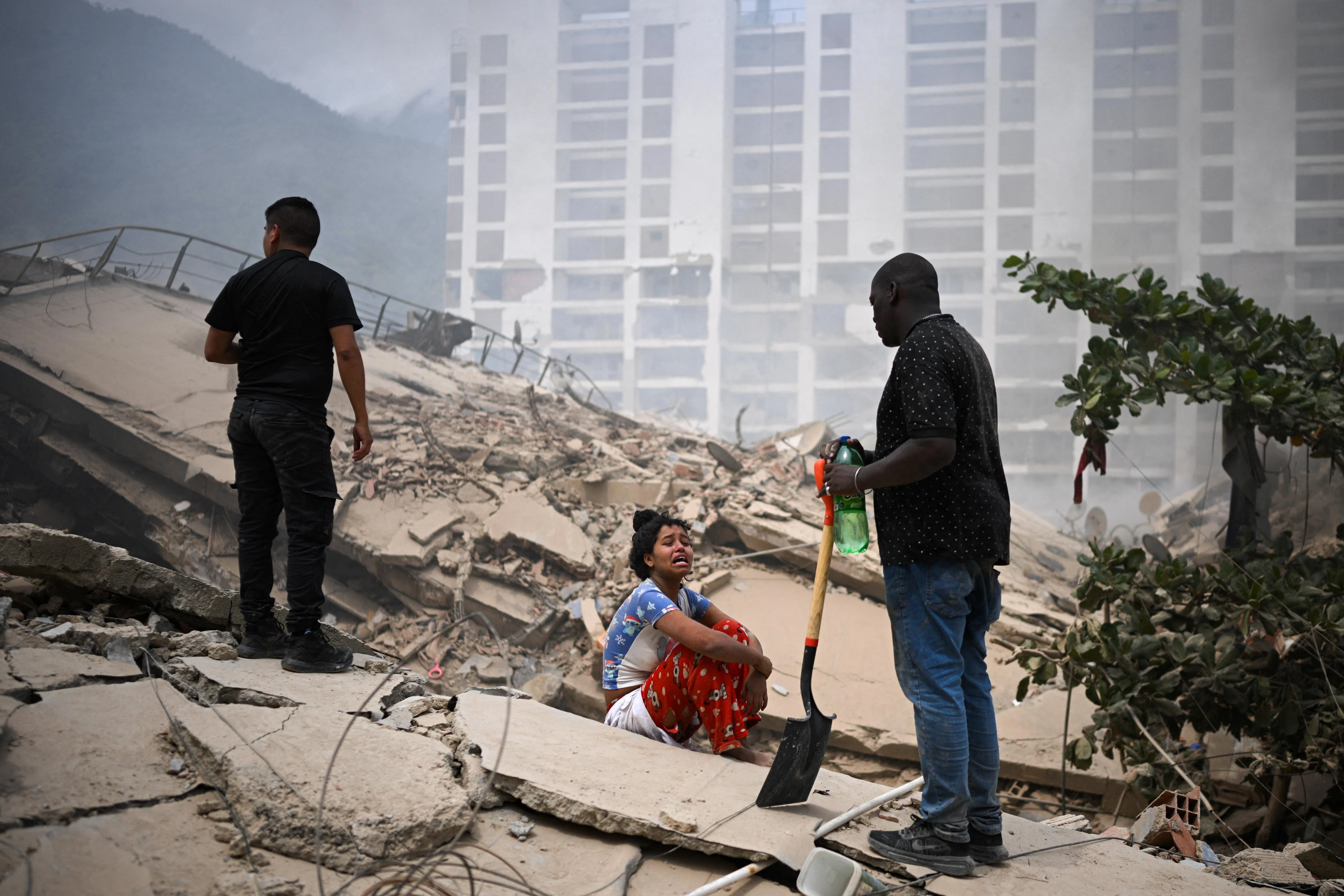 A woman reacts as people search for casualties amid the rubble of collapsed buildings, in the aftermath of earthquakes in La Guaira, Venezuela, June 25, 2026. REUTERS/Gaby Oraa