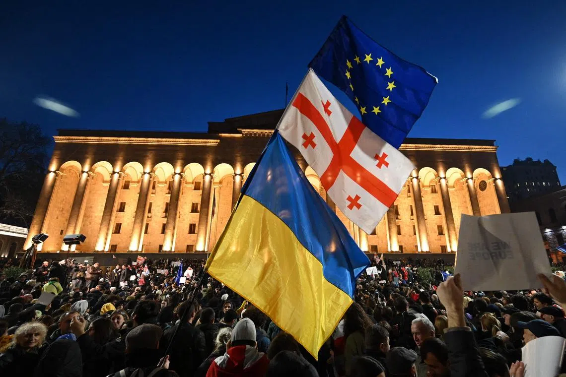 Protesters wave the EU, Georgian, and Ukrainian flags during a protest outside Georgia's Parliament in Tbilisi, on March 8, 2023.