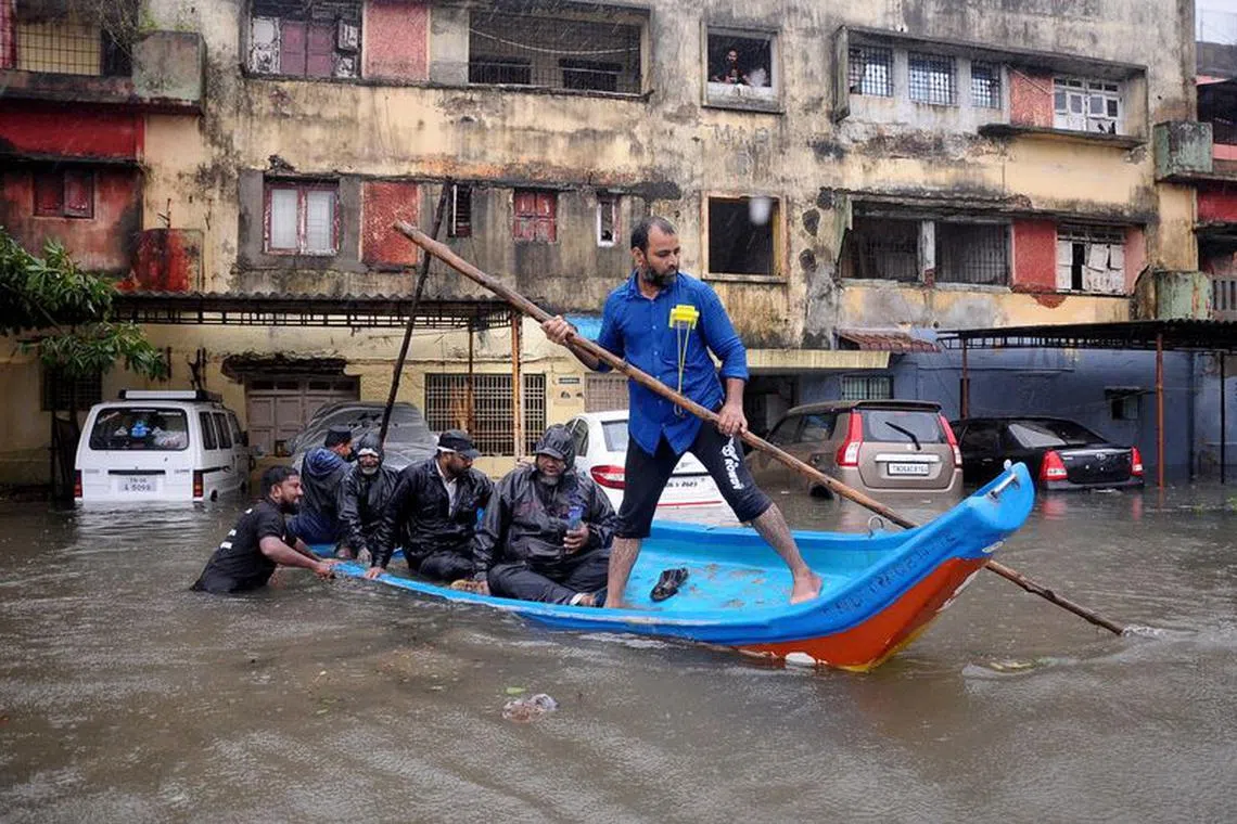 People move in a boat past partially submerged vehicles in a residential area following heavy rains ahead of Cyclone Michaung in Chennai, India, December 4, 2023. REUTERS/Stringe