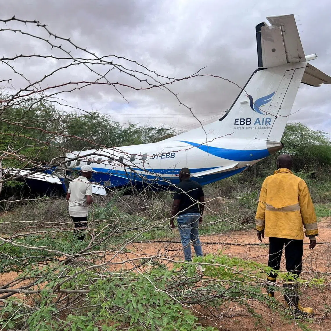 Rescuers walk towards an Embraer plane, operated by Kenyan carrier EBB Air, on a thicket after it overran the runway while landing in Mandera, Kenya, April 24, 2026. REUTERS/Stringer