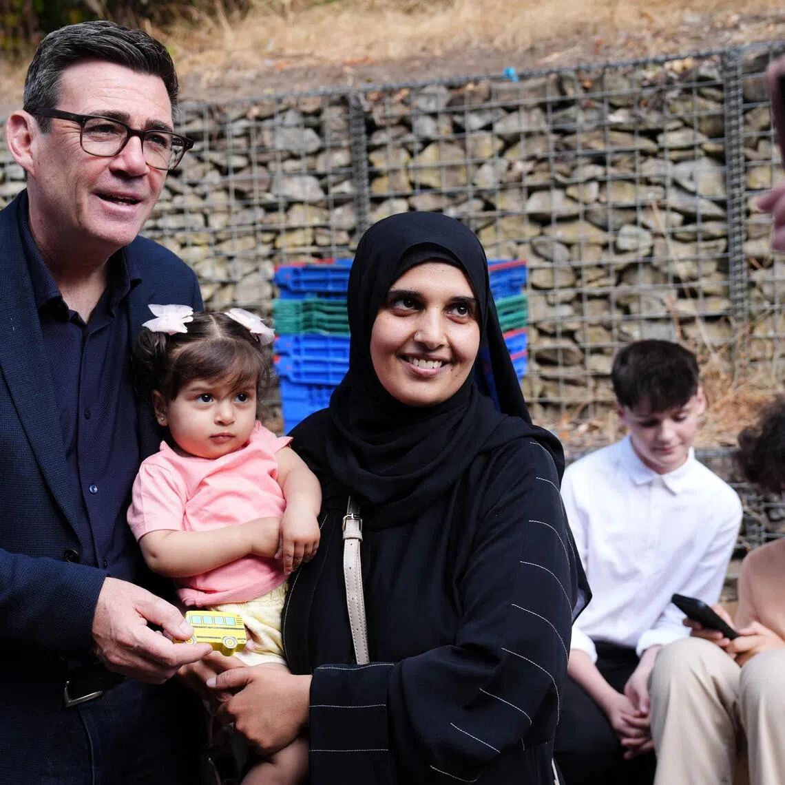 Britain’s Prime Minister Andy Burnham with a mother and child during a visit to a family centre in Sheffield, northern England, on July 31.