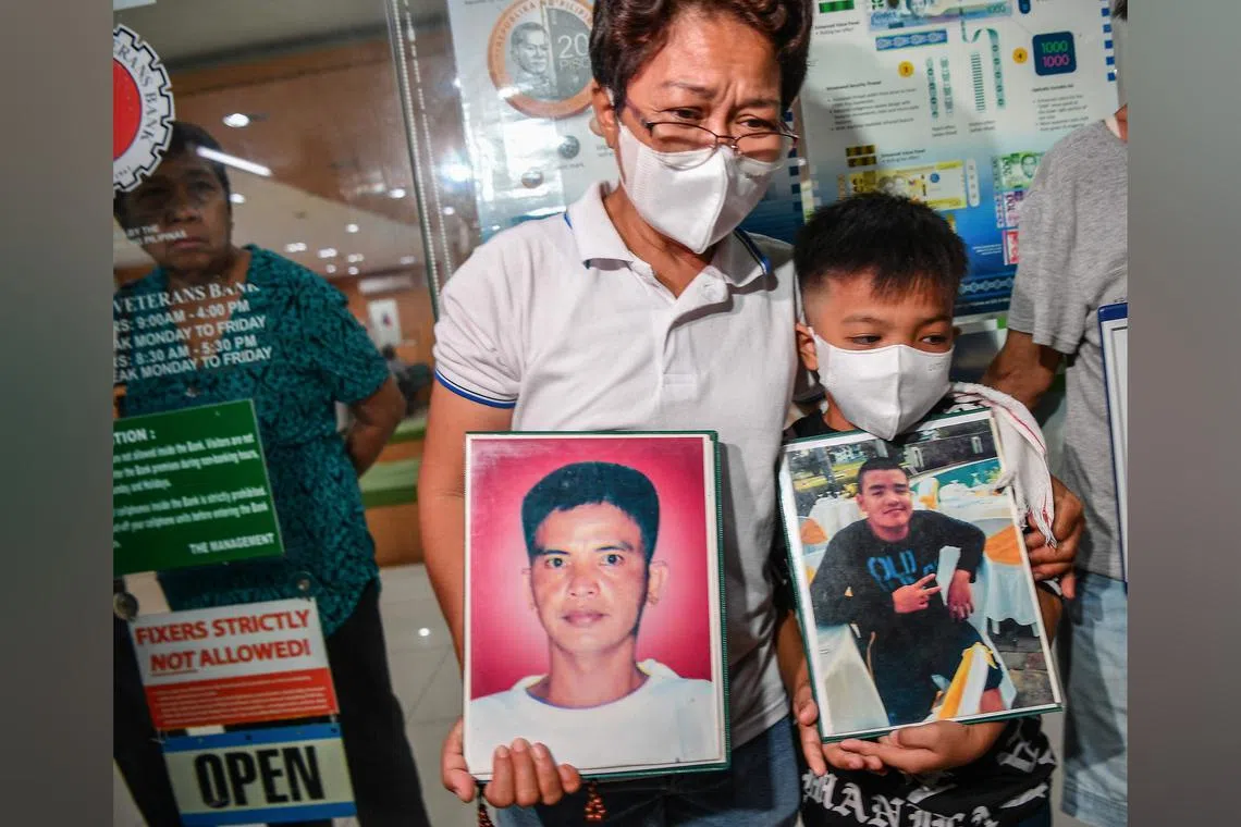 Ms Mary Ann Domingo and her son hold photos of her husband and son after four policemen were found guilty of killing them on June 18, 2024.