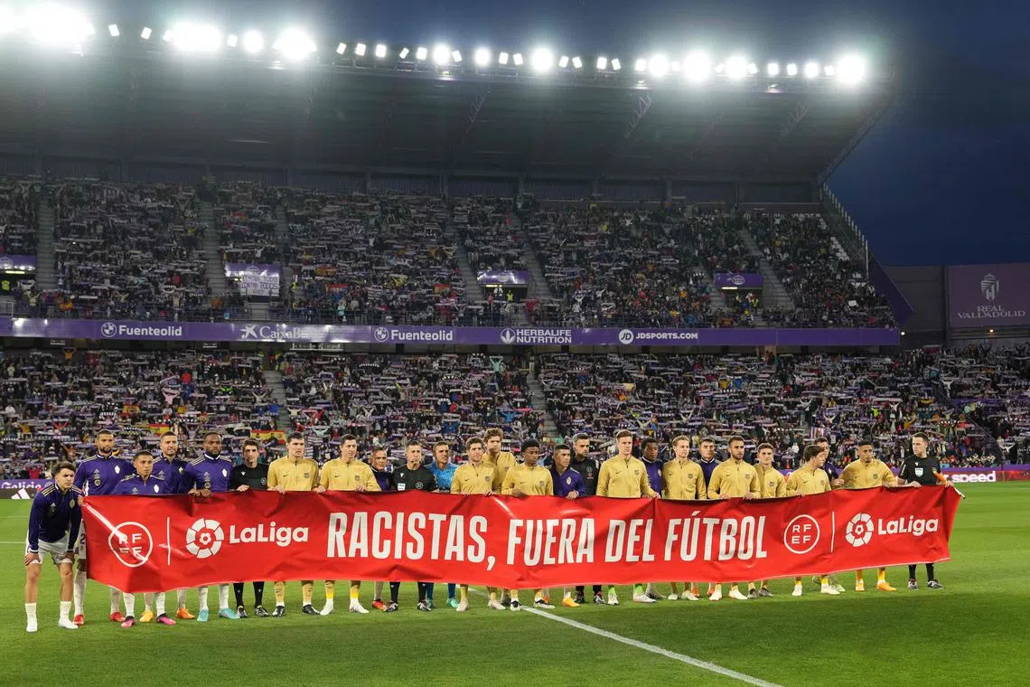 Players and match officials holding a banner reading "Racists, out of football" at half-time during the match between Real Valladolid and Barcelona at the Jose Zorilla stadium in Valladolid on May 23.