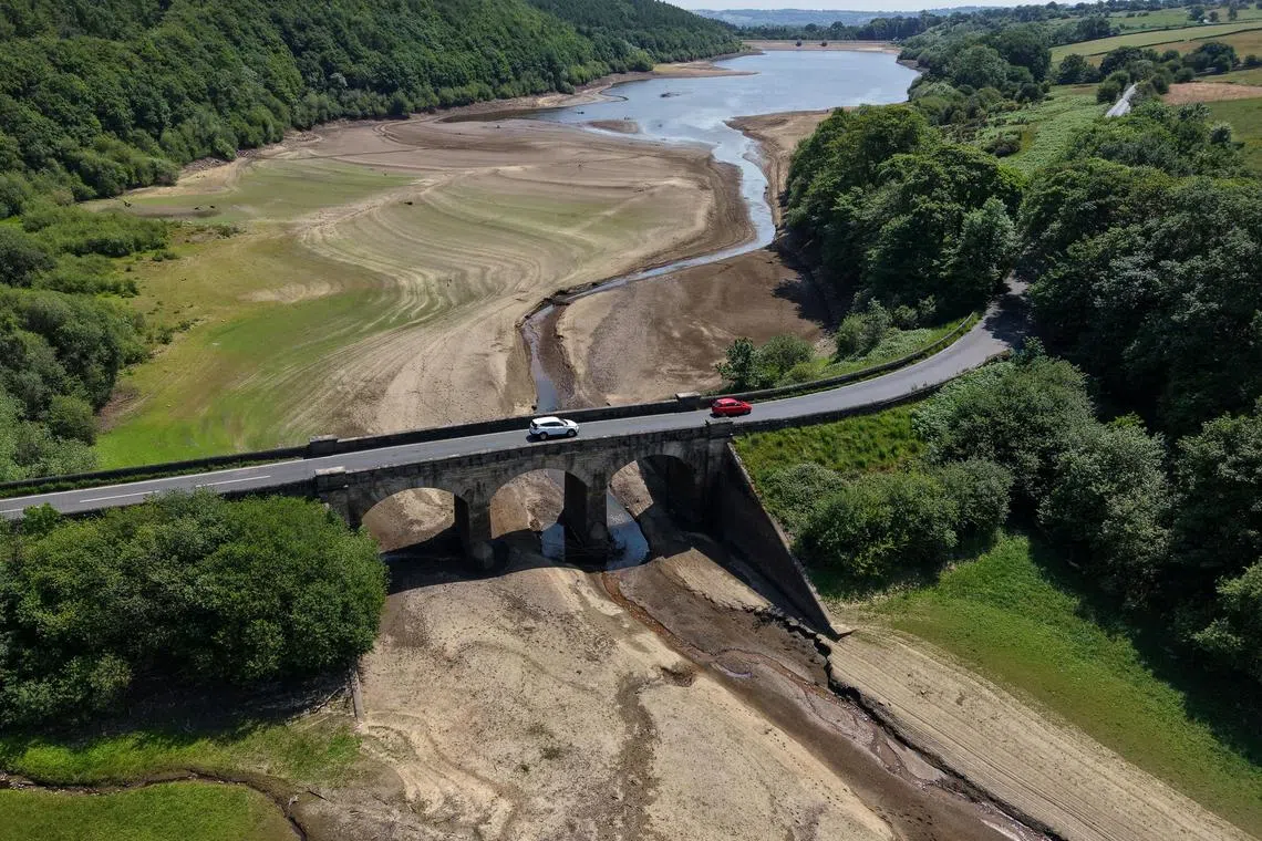 Vehicles passing over a bridge across a dry section of the Lindley Wood Reservoir after a prolonged period without rain saw water levels drop near Otley, Britain, June 19, 2025.