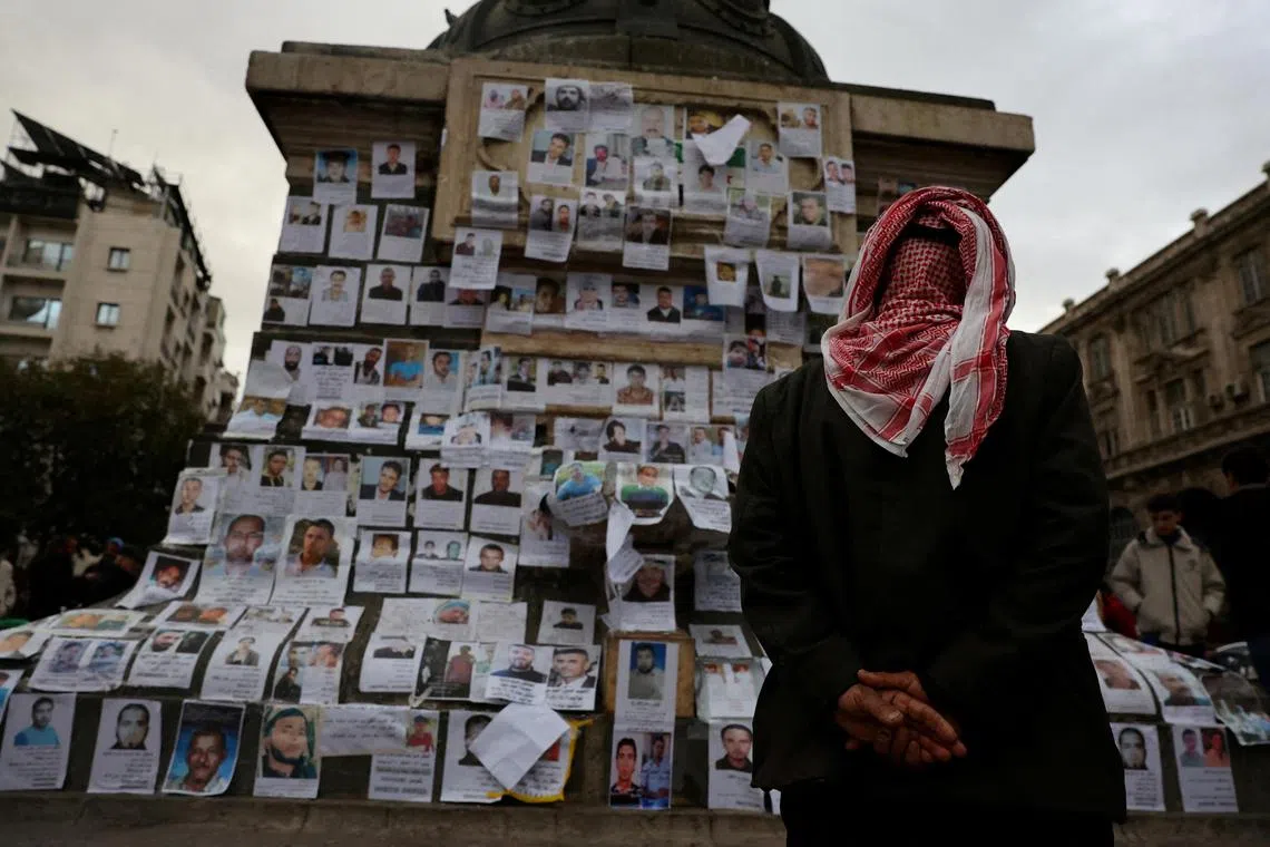 A man looking at pictures of missing people, believed to be prisoners of Saydnaya prison, which was known as a "slaughterhouse" under the rule of ousted leader Bashar al-Assad.