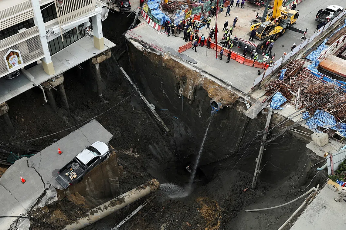 A vehicle teeters on the edge of a massive sinkhole that opened on Samsen Road near Vajira Hospital, in Bangkok, Thailand, September 24, 2025. REUTERS/Chalinee Thirasupa     TPX IMAGES OF THE DAY     