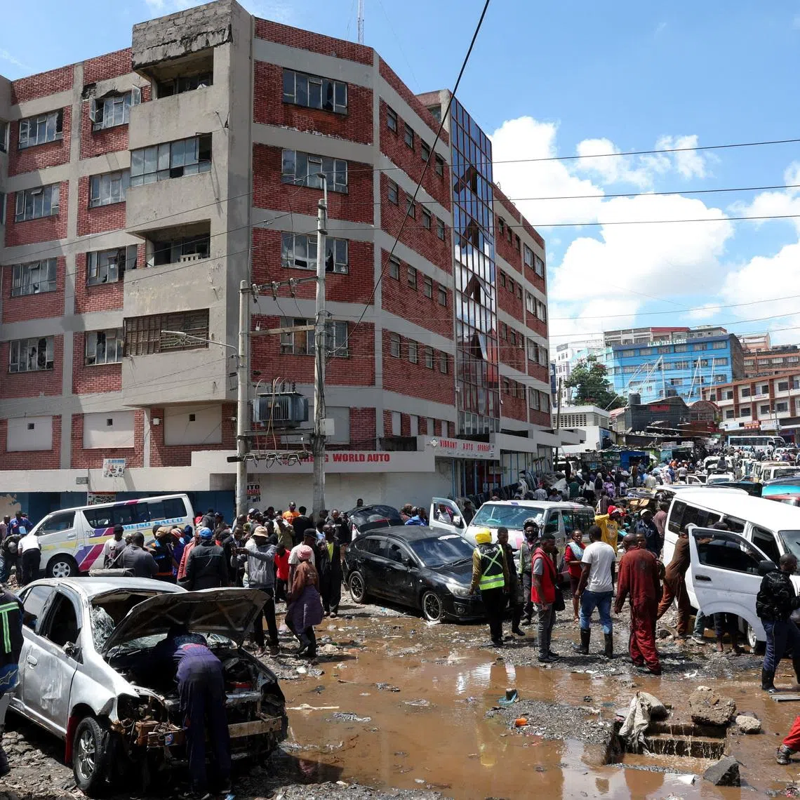FILE PHOTO: People stand around destroyed vehicles following flash floods caused by heavy rainfall in the Grogan area, popular for automotive workshops and secondhand spare parts, in downtown Nairobi, Kenya, March 7, 2026. REUTERS/Monicah Mwangi/File Photo